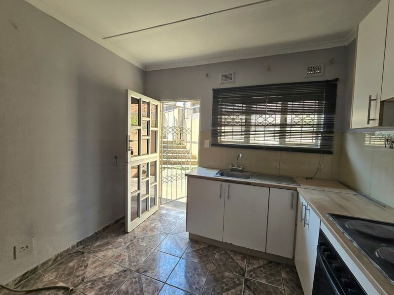 A functional kitchen featuring built-in cabinetry, a stainless steel sink, and an integrated oven, with direct access to an outdoor area.