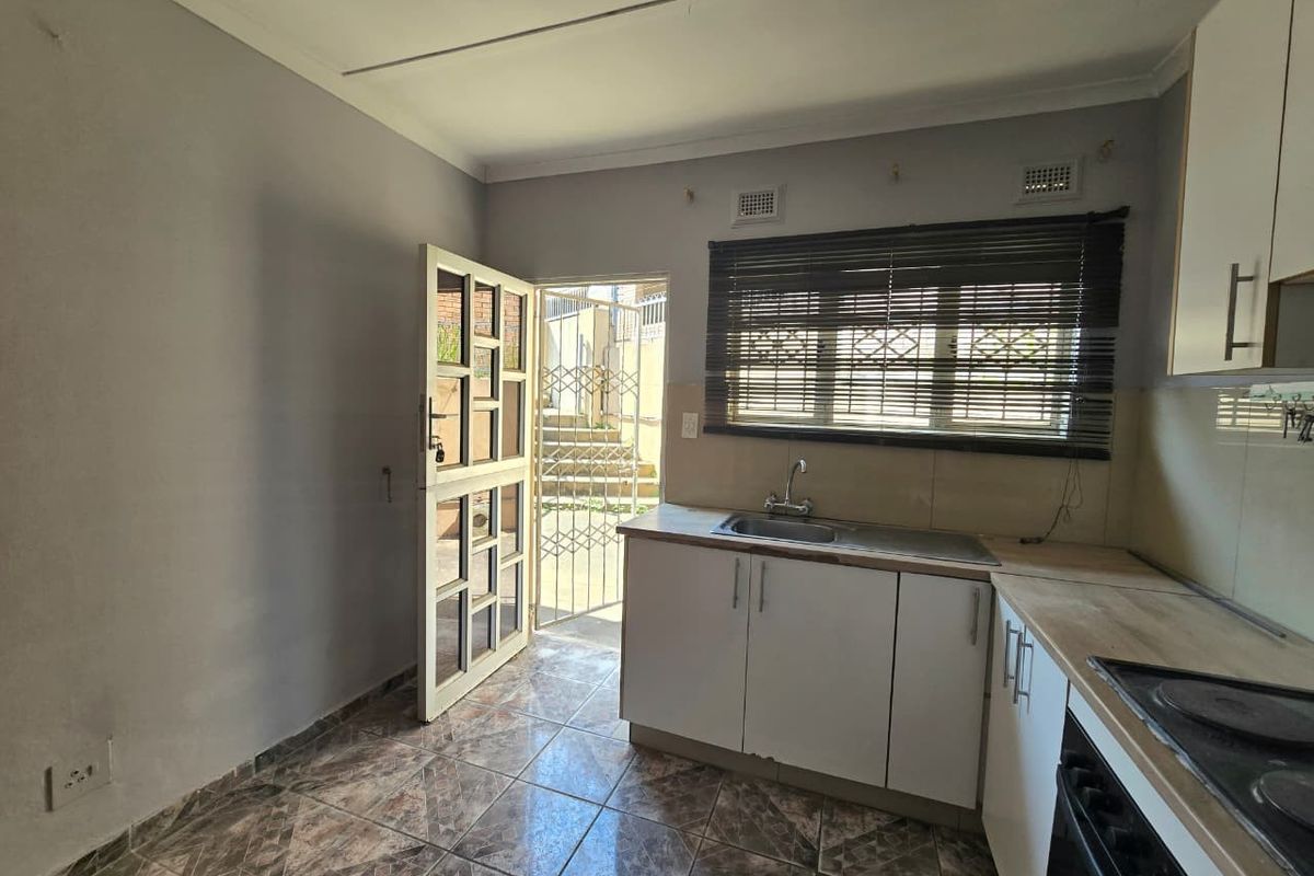 A functional kitchen featuring built-in cabinetry, a stainless steel sink, and an integrated oven, with direct access to an outdoor area.