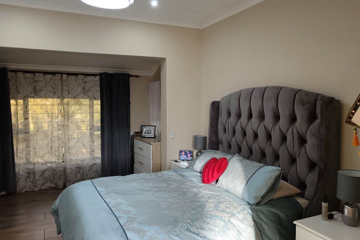 A well-maintained bedroom featuring tiled flooring, a recessed window area, and neutral wall tones, providing a comfortable and functional living space.