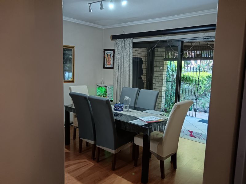 Dining room featuring laminate flooring, coved ceilings, and sliding glass doors providing direct access to the outdoor patio area.