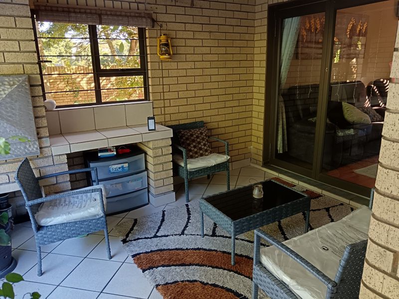 Covered patio area featuring exposed brick walls, tiled flooring, and a built-in brick counter, providing a functional outdoor living space.
