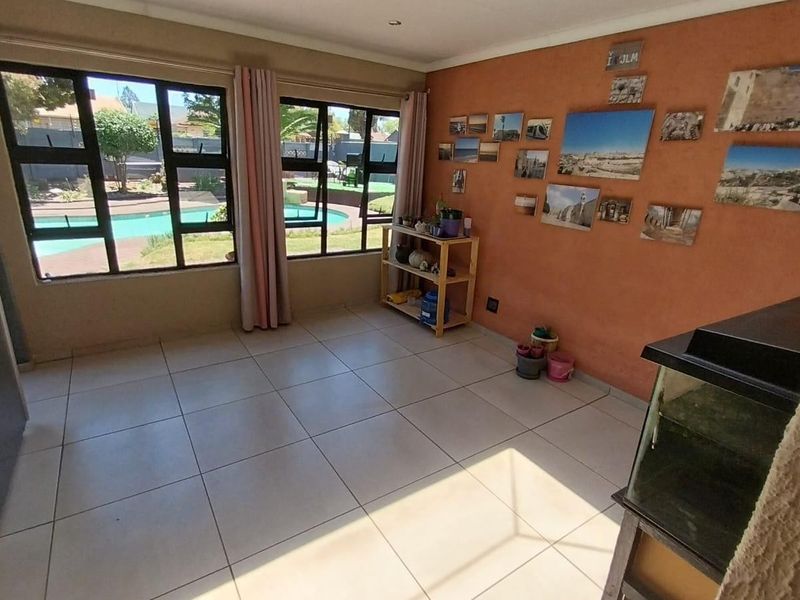 A bright living area featuring large windows with views of the pool area, tiled flooring, and neutral wall finishes.