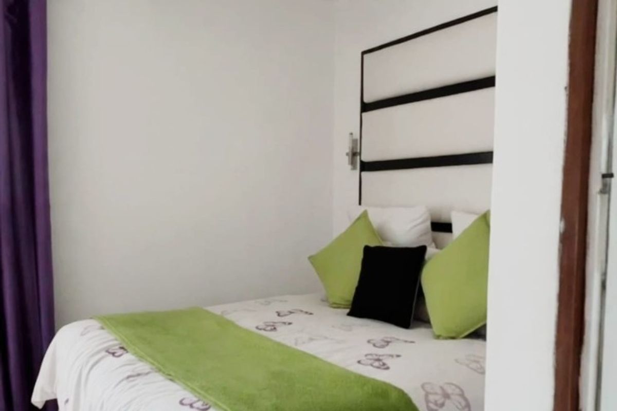 A compact bedroom featuring tiled flooring and a built-in headboard, offering a functional and clean living space.