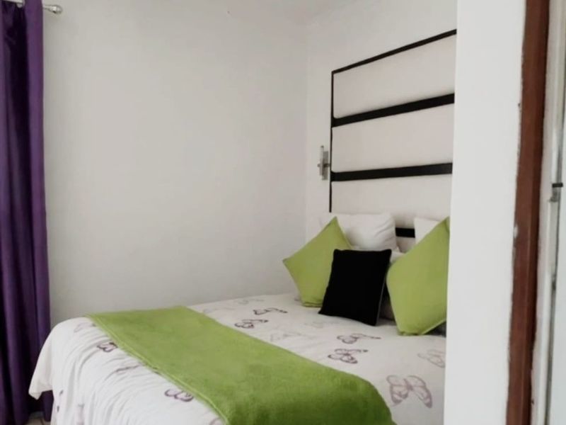 A compact bedroom featuring tiled flooring and a built-in headboard, offering a functional and clean living space.