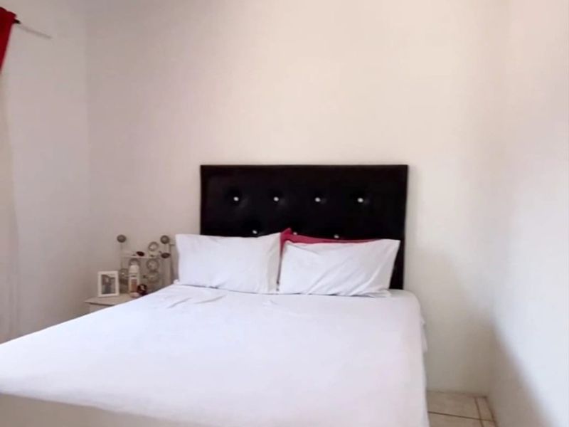 A simple bedroom featuring tiled flooring and neutral wall finishes, providing a clean and functional space.