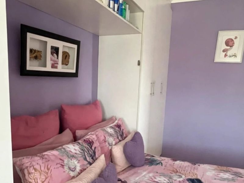 A bedroom featuring built-in cupboards and overhead storage cabinetry with a functional layout.
