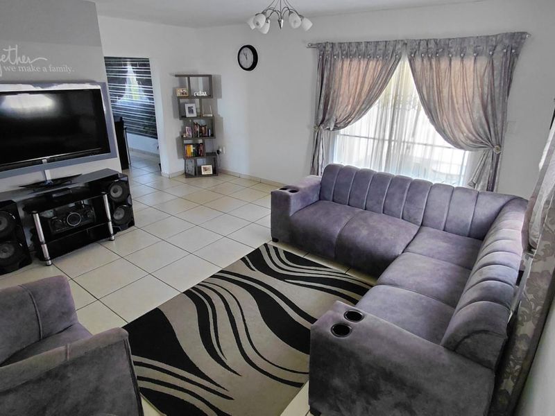 A living room featuring tiled flooring and a sliding glass door providing natural light.