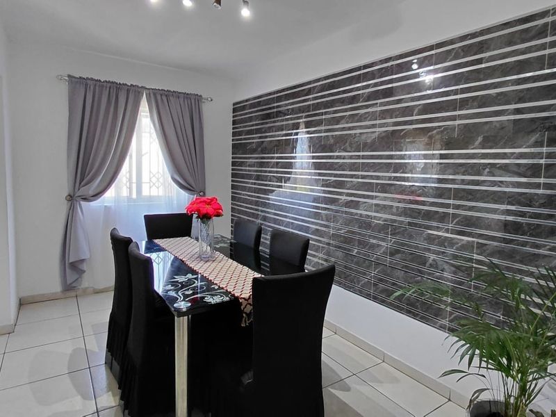 Dining room featuring tiled flooring and a modern dark marble-effect feature wall, providing a clean and contemporary space for meals.