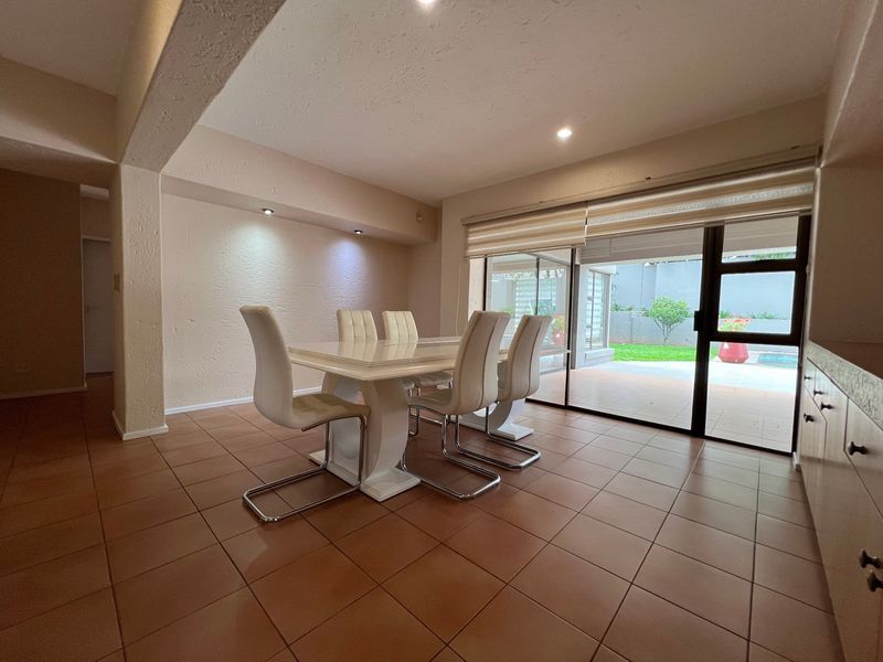 Open plan dining area featuring ceramic tile flooring, recessed lighting, and large sliding glass doors providing direct access to the patio and pool area.