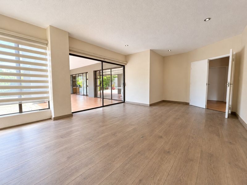 Spacious, light-filled living area featuring modern laminate flooring, recessed lighting, and large sliding glass doors that open onto an outdoor patio space.