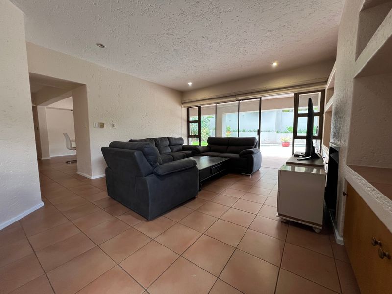 Spacious living room featuring tiled flooring, built-in shelving, a fireplace, and large sliding glass doors providing direct access to the outdoor patio area.