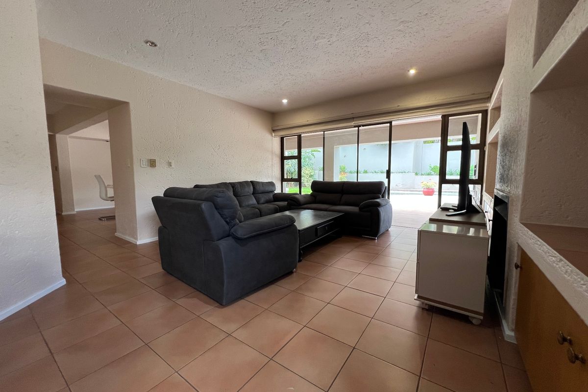 Spacious living room featuring tiled flooring, built-in shelving, a fireplace, and large sliding glass doors providing direct access to the outdoor patio area.