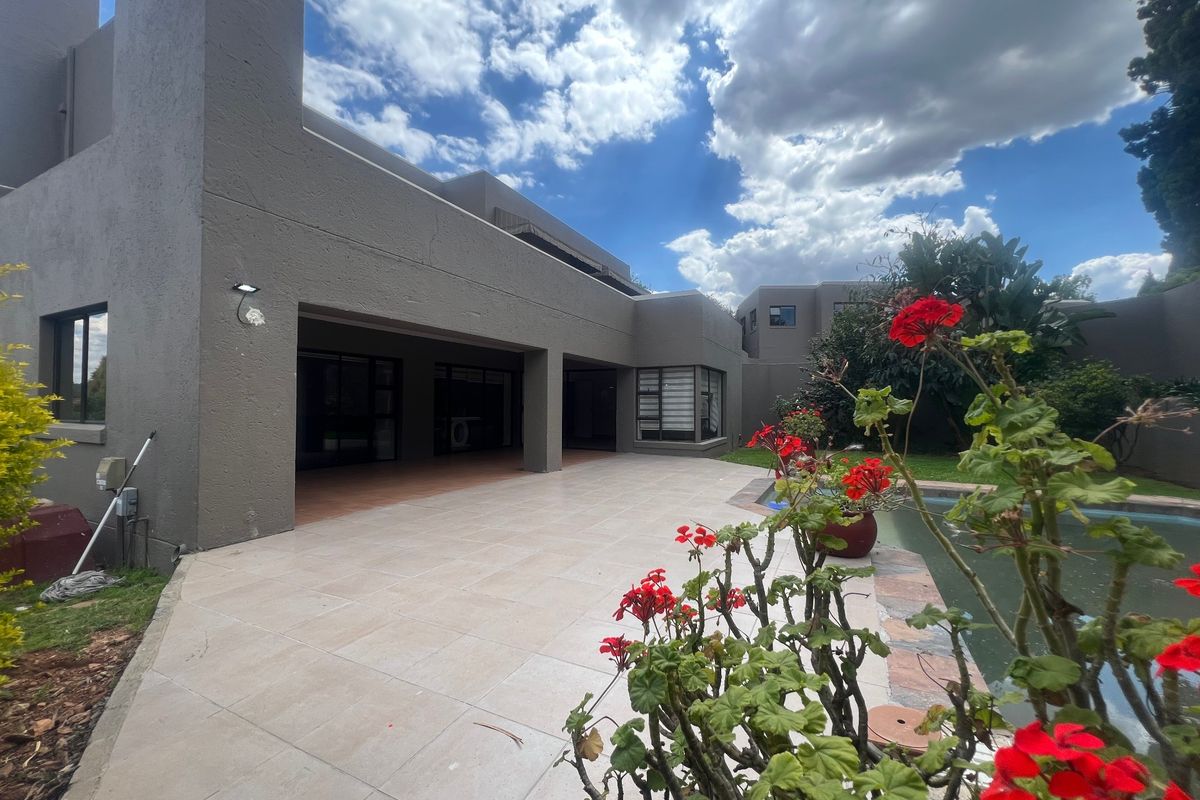 Rear view of the property featuring a spacious tiled patio, swimming pool, and well-maintained exterior walls with large sliding doors.