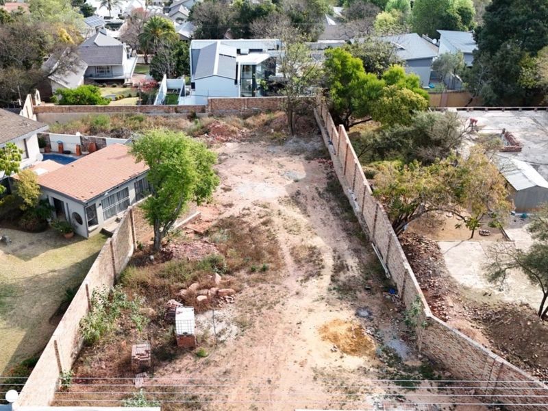 Aerial view of a vacant residential plot enclosed by perimeter brick boundary walls, offering a clear space for future development.