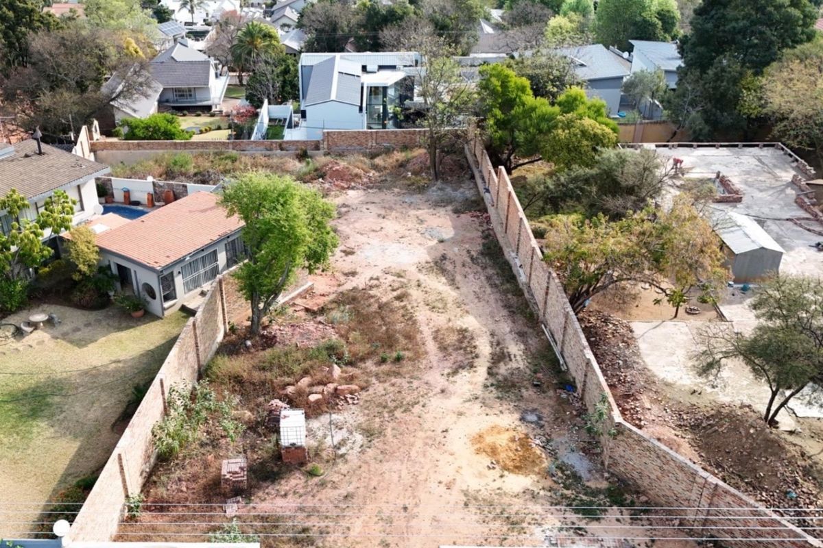 Aerial view of a vacant residential plot enclosed by perimeter brick boundary walls, offering a clear space for future development.