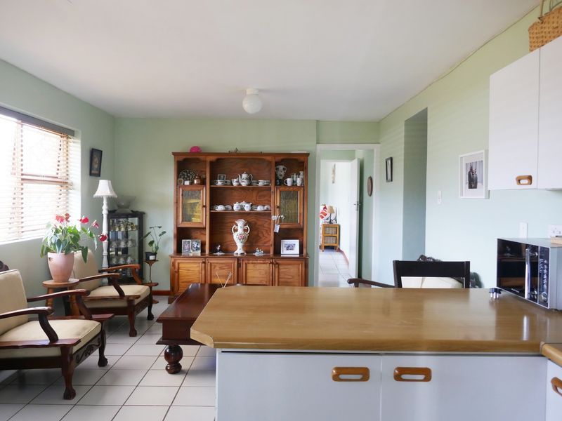 Open plan living and kitchen area featuring tiled flooring, neutral wall tones, and functional cabinetry with laminate countertops.