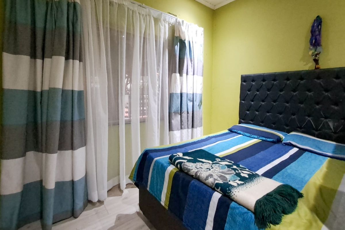 A standard bedroom featuring laminate flooring and window treatments, offering a functional space ready for personalization.