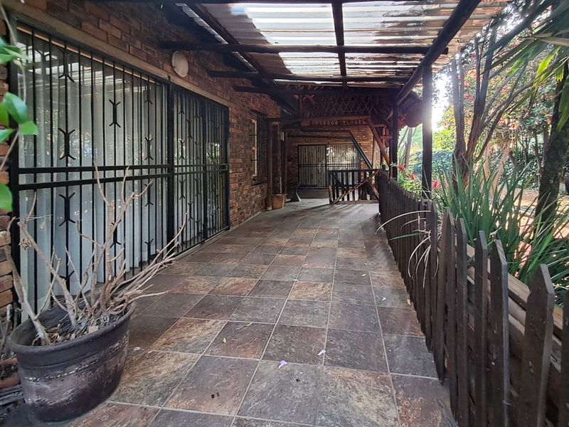 A covered outdoor patio area featuring tiled flooring, brick wall finishes, and a timber fence, providing a functional space for outdoor relaxation.