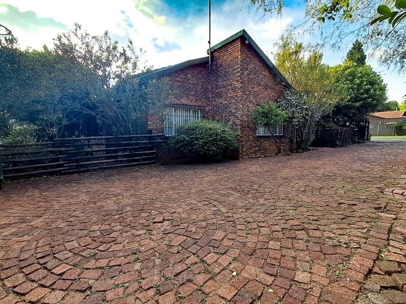 Front exterior view of a face brick house featuring a circular pattern paved driveway and security bars on the windows.