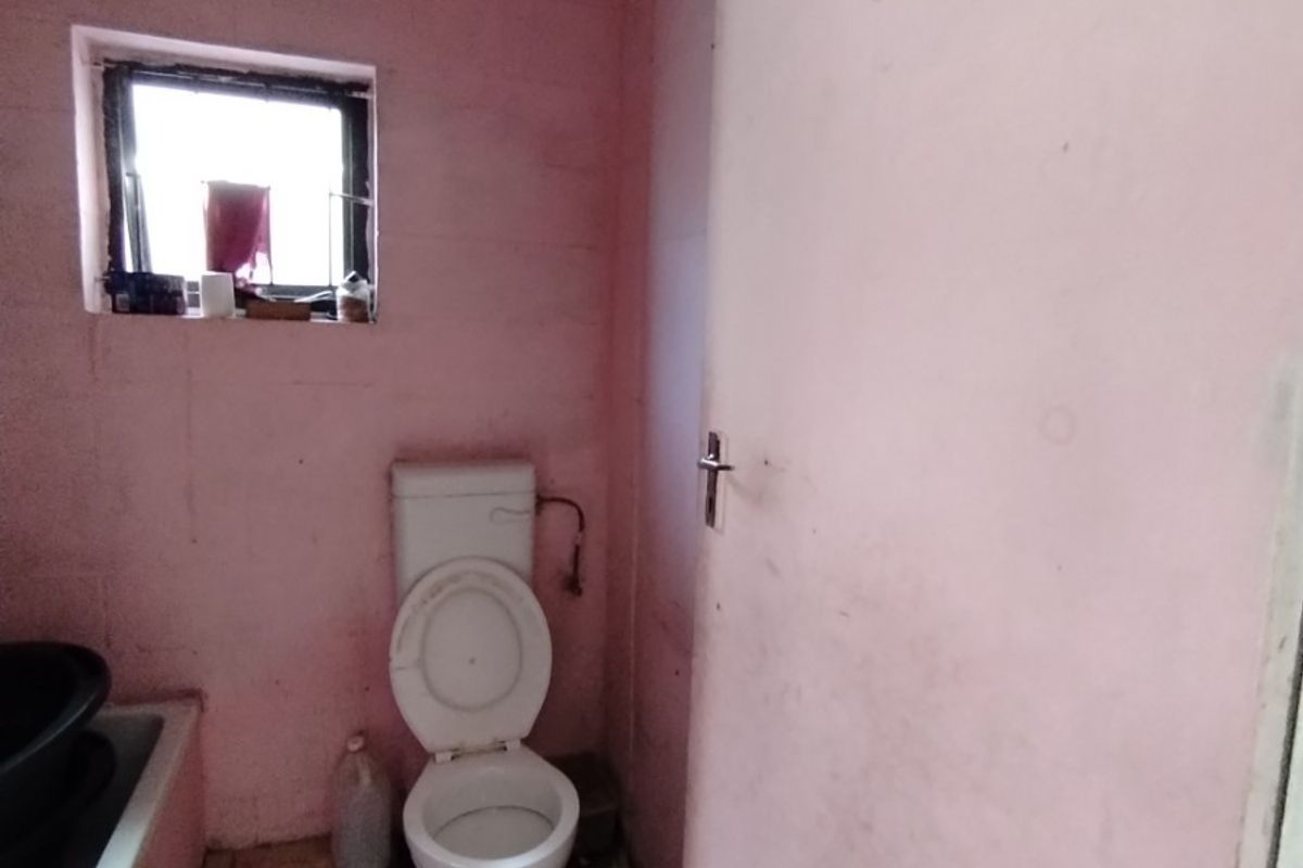 A small, dated bathroom featuring a toilet and bathtub, requiring significant renovation and cosmetic updates to improve its condition and functionality.