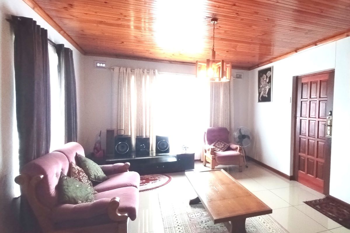 A living room featuring a warm timber tongue and groove ceiling, tiled flooring, and a solid wood panel entrance door.