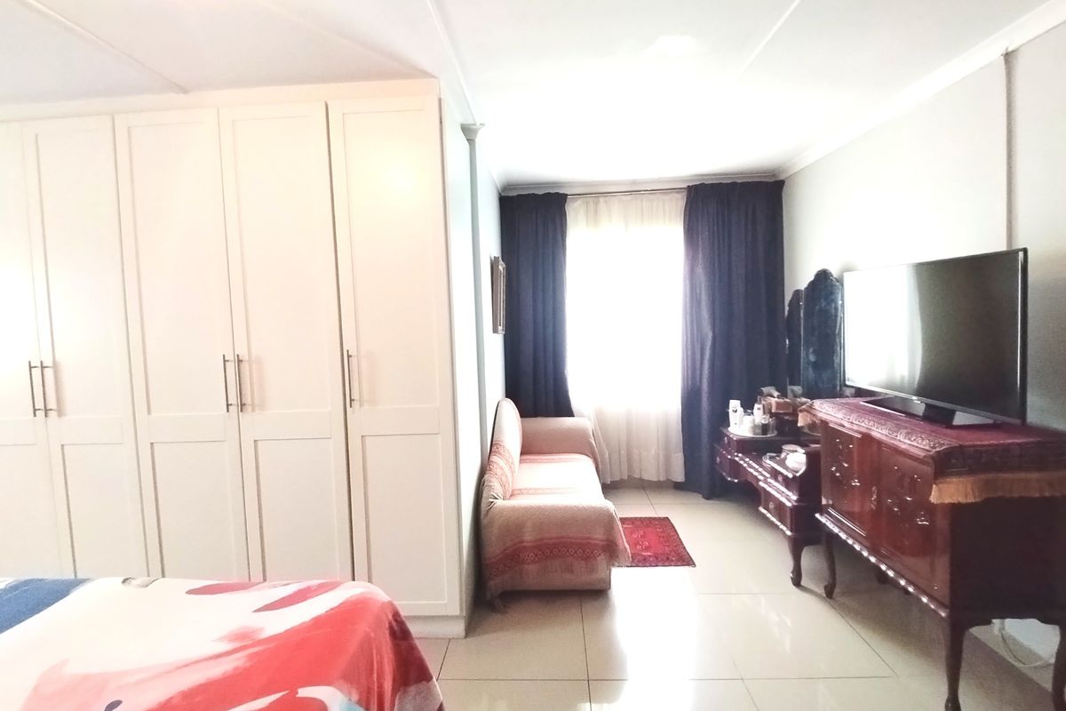 A bedroom featuring built-in cupboards and tiled flooring, offering a functional layout with natural light from the window.