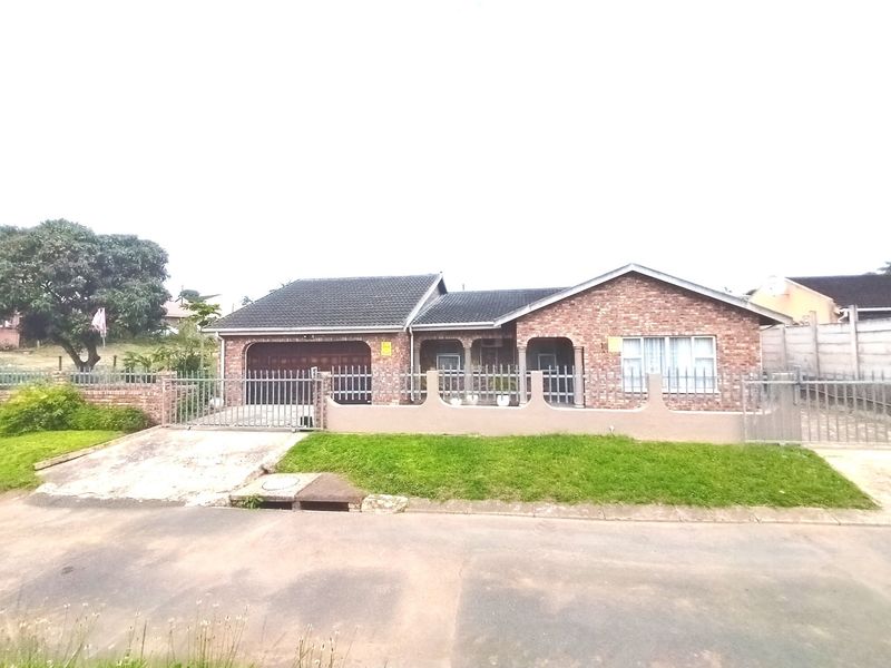 A single-story face brick house featuring a tiled roof, integrated garage, and a front boundary wall with a metal gate.