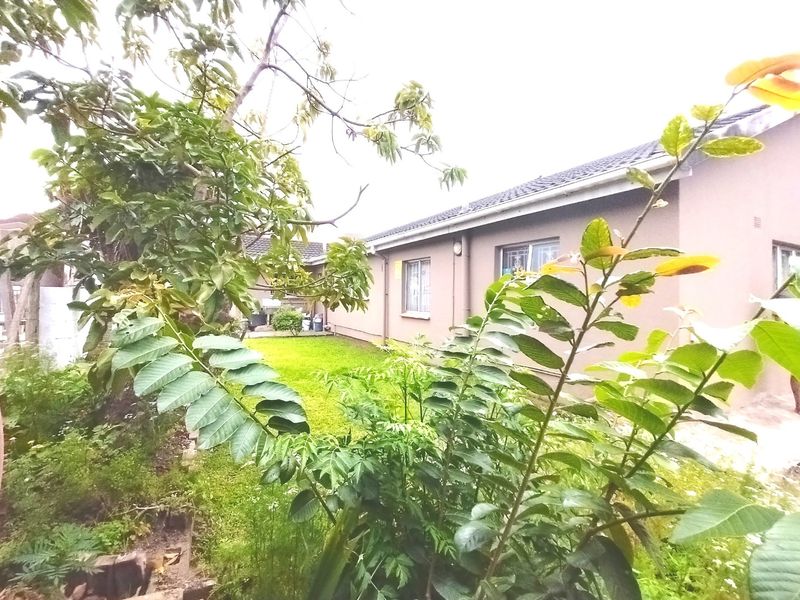 A view of the rear exterior of the house featuring a lawn and garden area with security bars on the windows.
