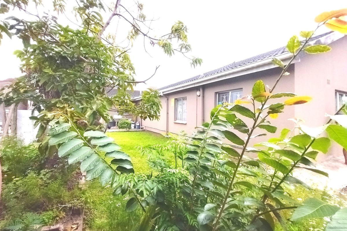 A view of the rear exterior of the house featuring a lawn and garden area with security bars on the windows.