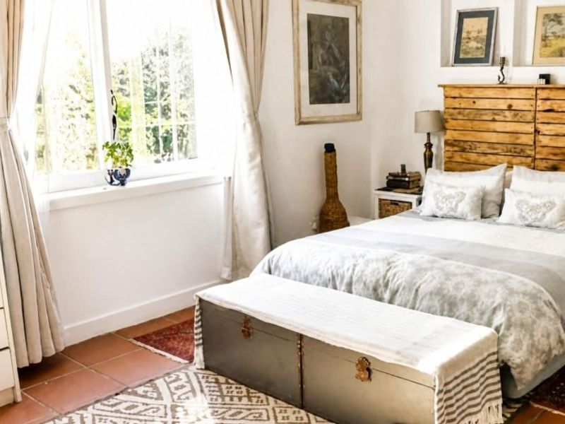 A cozy bedroom featuring terracotta floor tiles and built-in recessed wall niches, offering a warm and inviting atmosphere with natural light.