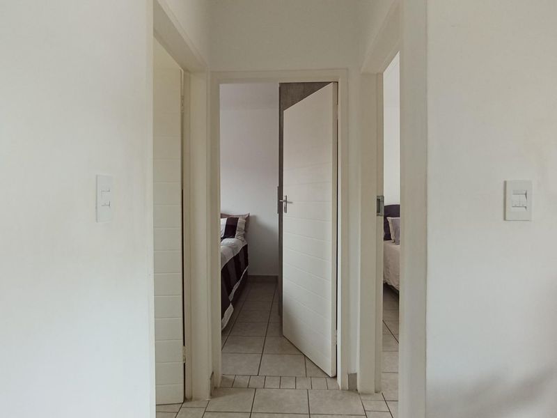 A clean and functional hallway featuring tiled flooring and access to multiple bedrooms.