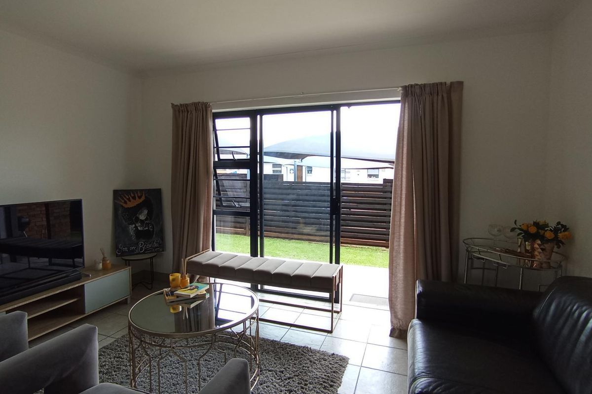 A bright living room featuring tiled flooring and a large sliding glass door providing direct access to the outdoor area.