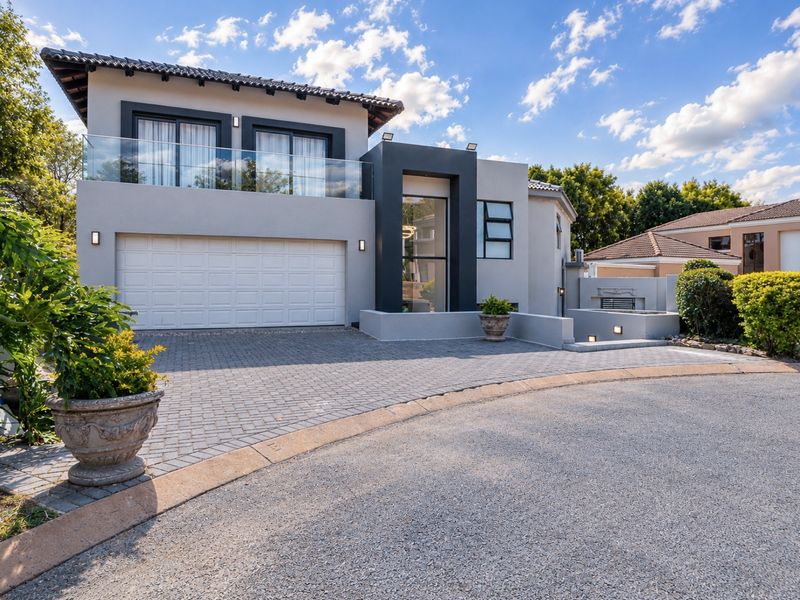Modern double-story residential property featuring a paved driveway, double garage, and a glass-fronted balcony with contemporary architectural finishes.