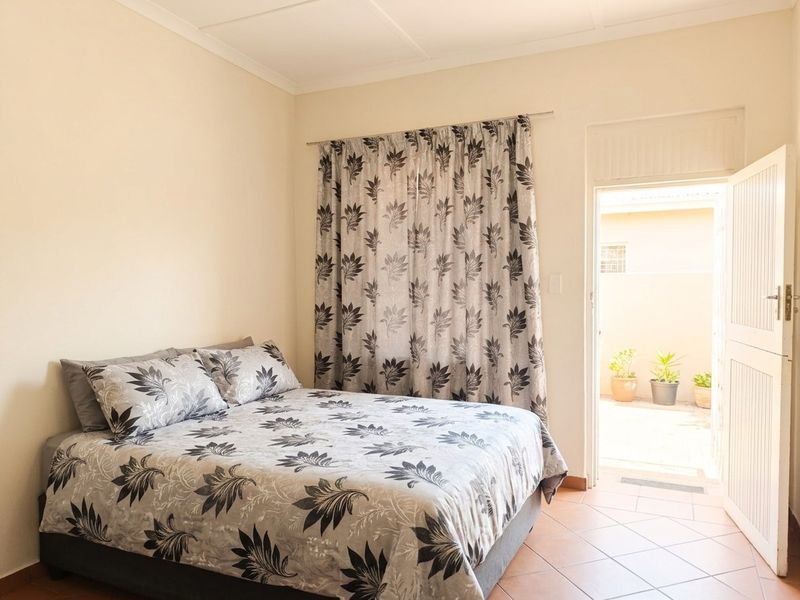 A bedroom featuring tiled flooring and direct access to an outdoor area through a private door.
