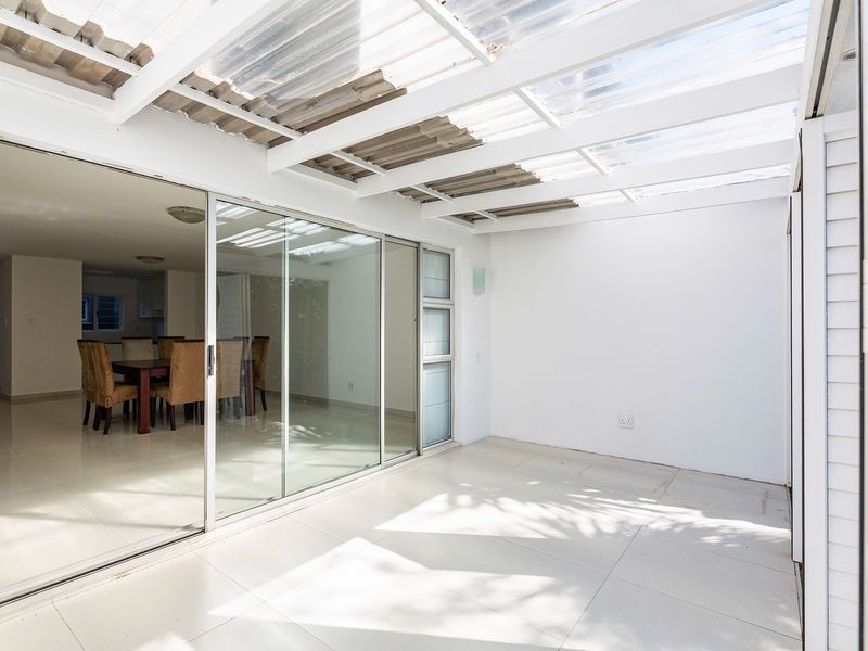A covered patio area featuring a translucent roof, tiled flooring, and large sliding glass doors providing seamless access to the interior living space.