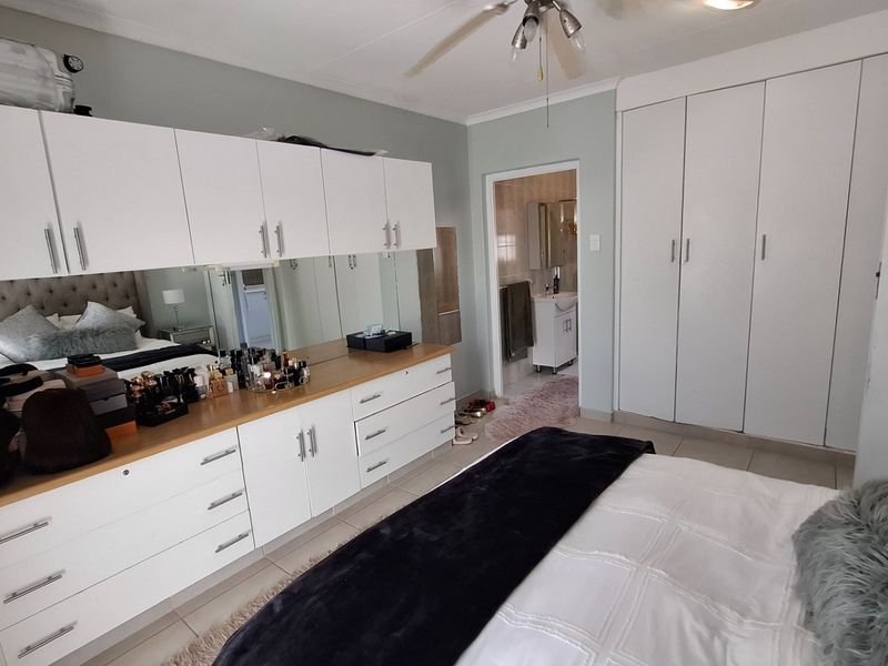 Spacious bedroom featuring extensive built-in cabinetry, a ceiling fan, and direct access to an en-suite bathroom.