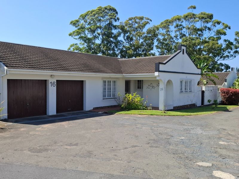 Front elevation of a townhouse featuring a double garage, tiled roof, and paved driveway access.