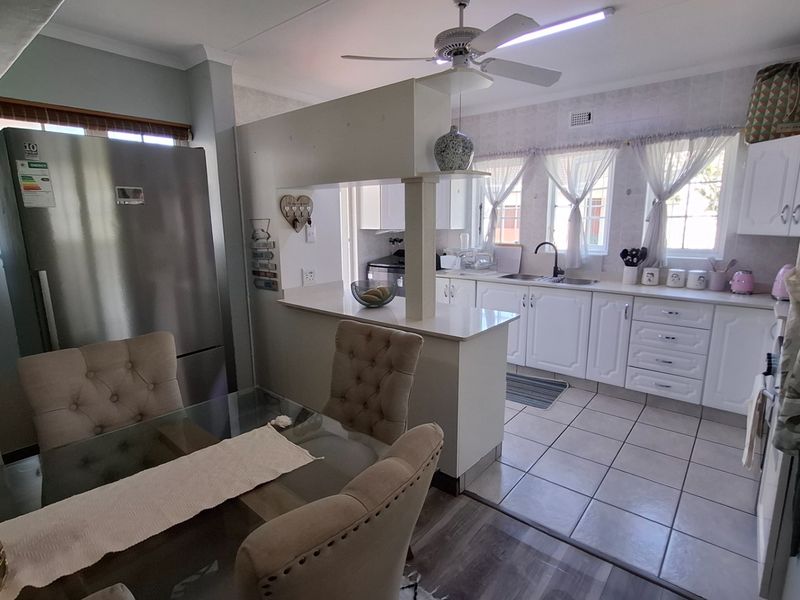 Open plan kitchen and dining area featuring white cabinetry, a breakfast bar, tiled kitchen flooring, and a ceiling fan.