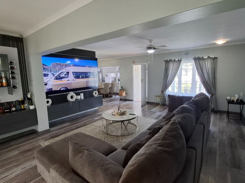 Spacious open-plan living area featuring modern laminate flooring, built-in cabinetry, and a ceiling fan, creating a comfortable and well-maintained space.