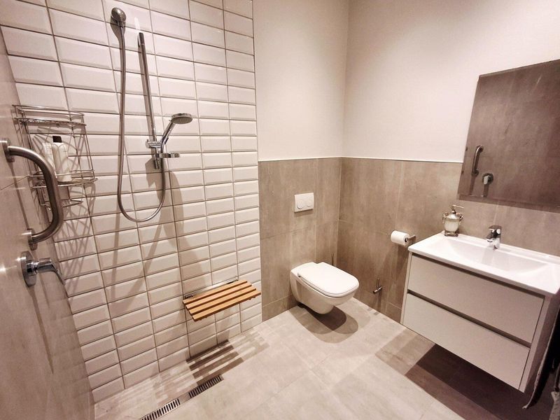 Modern bathroom featuring a walk-in shower with subway tiling, wall-mounted toilet, and a sleek vanity unit with integrated sink.