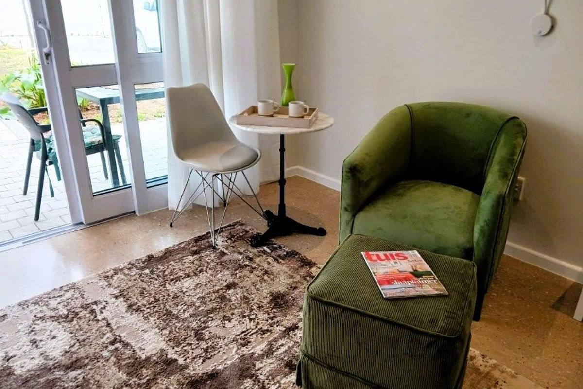 A bright living area featuring polished concrete floors and a large sliding glass door providing direct access to an outdoor patio space.