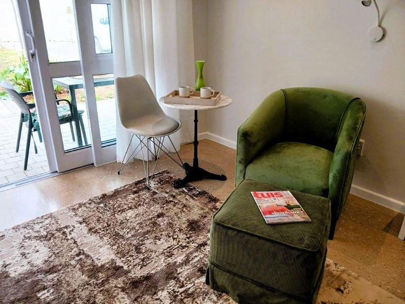 A bright living area featuring polished concrete floors and a large sliding glass door providing direct access to an outdoor patio space.