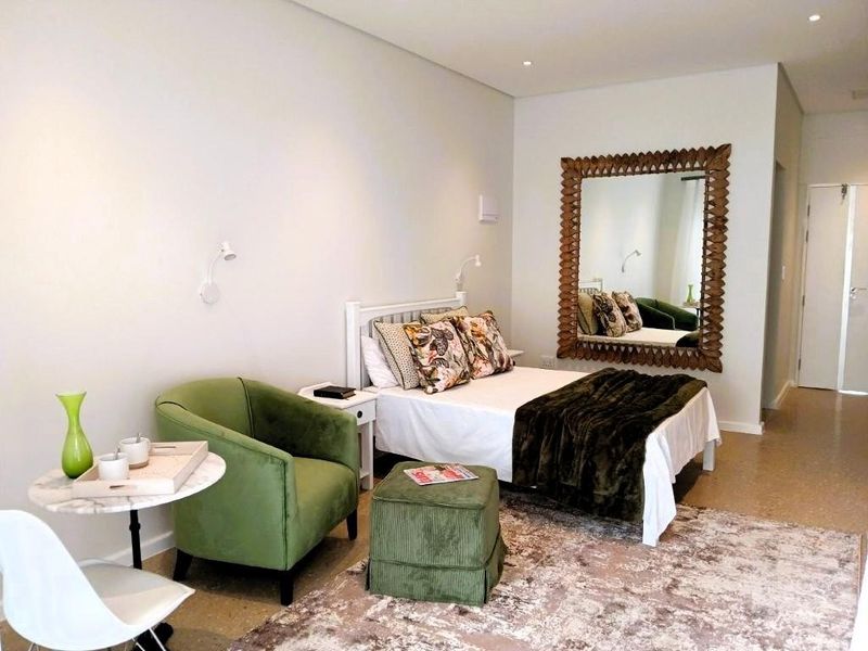 A well-maintained bedroom featuring polished concrete flooring, recessed downlighting, and wall-mounted reading lights.