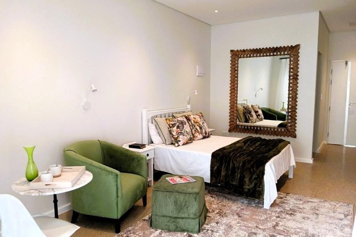 A well-maintained bedroom featuring polished concrete flooring, recessed downlighting, and wall-mounted reading lights.