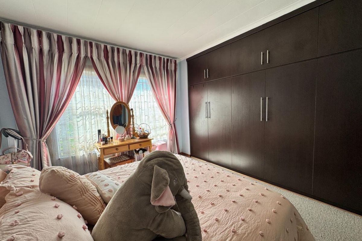 A well-maintained bedroom featuring extensive floor-to-ceiling built-in cupboards and carpeted flooring, offering ample storage space.