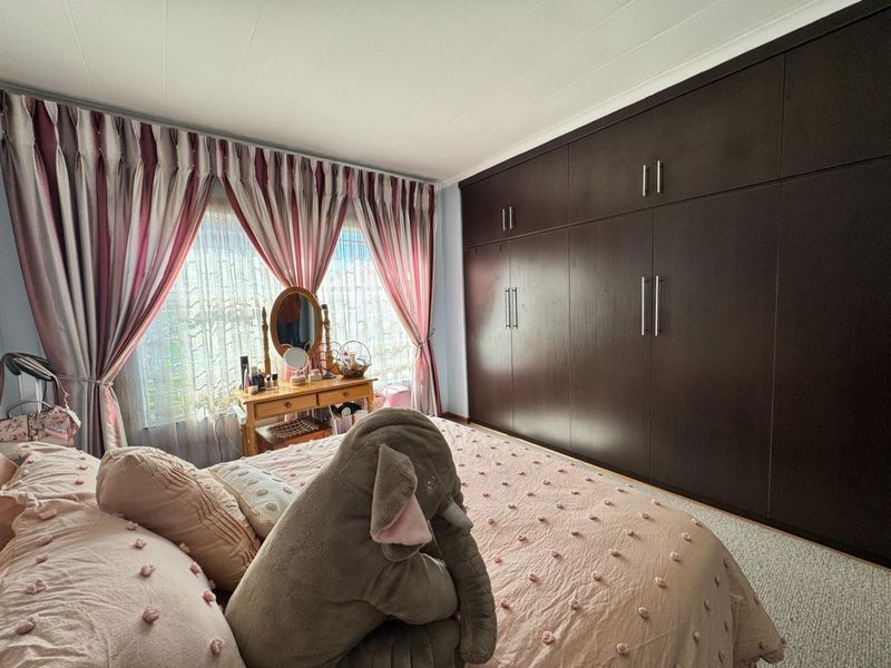 A well-maintained bedroom featuring extensive floor-to-ceiling built-in cupboards and carpeted flooring, offering ample storage space.