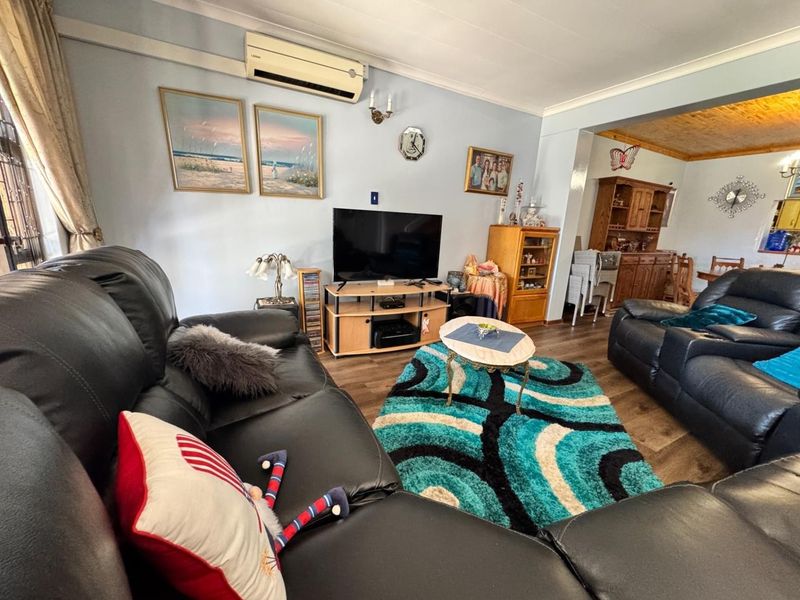 A comfortable living room featuring laminate flooring, coving, and a wall-mounted air conditioning unit, providing a functional and well-maintained living space.