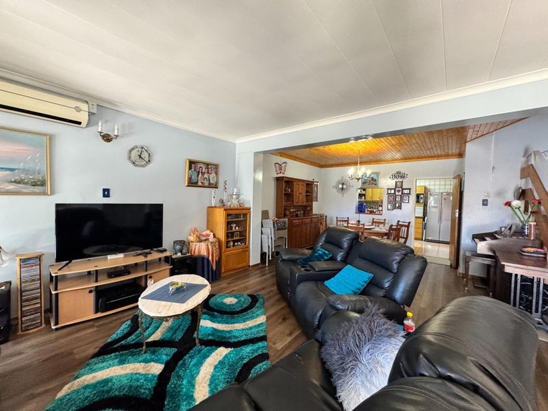 Spacious open-plan living and dining area featuring laminate flooring, coved ceilings, and a split-system air conditioner, offering a functional layout for family living.