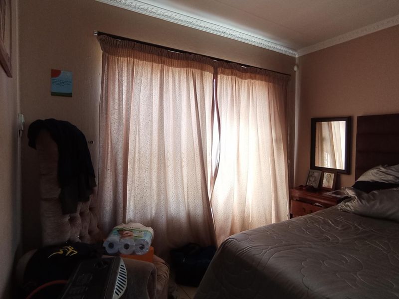 A bedroom featuring decorative ceiling cornicing and a large window with curtains, providing natural light to the space.