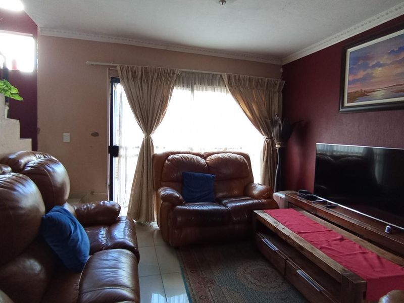 A comfortable living room featuring tiled flooring, crown molding, and a sliding glass door providing natural light and access to the exterior.